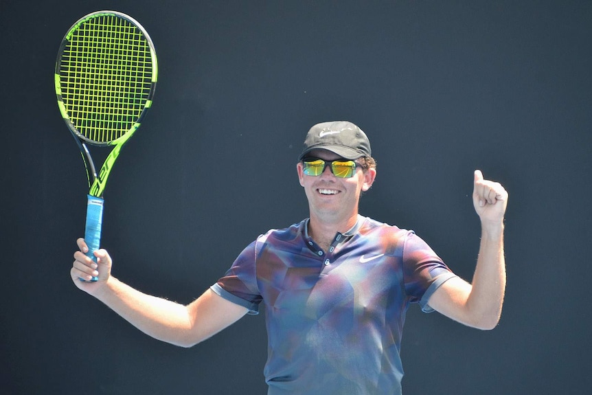Ipswich tennis player Archie Graham holds his racket in the air in triumph
