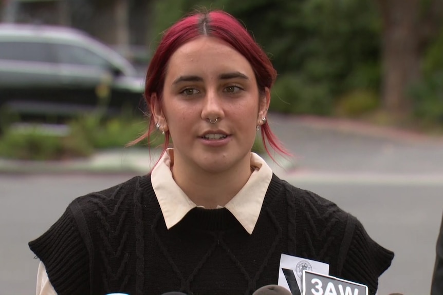 A woman with red hair speaks into a microphone. 