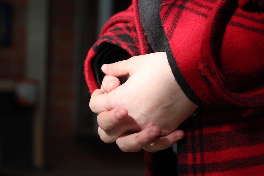 An unidentified victim of sexual assault stands with her hands crossed.