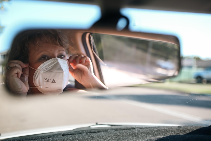 A woman driving while wearing a mask