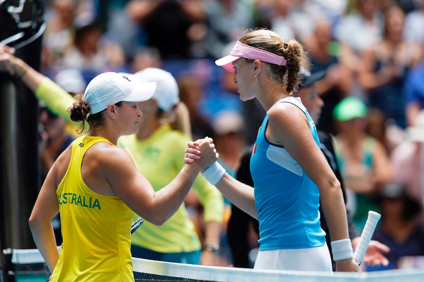 Two female tennis players shake hands at the net after a rubber in the Fed Cup final.