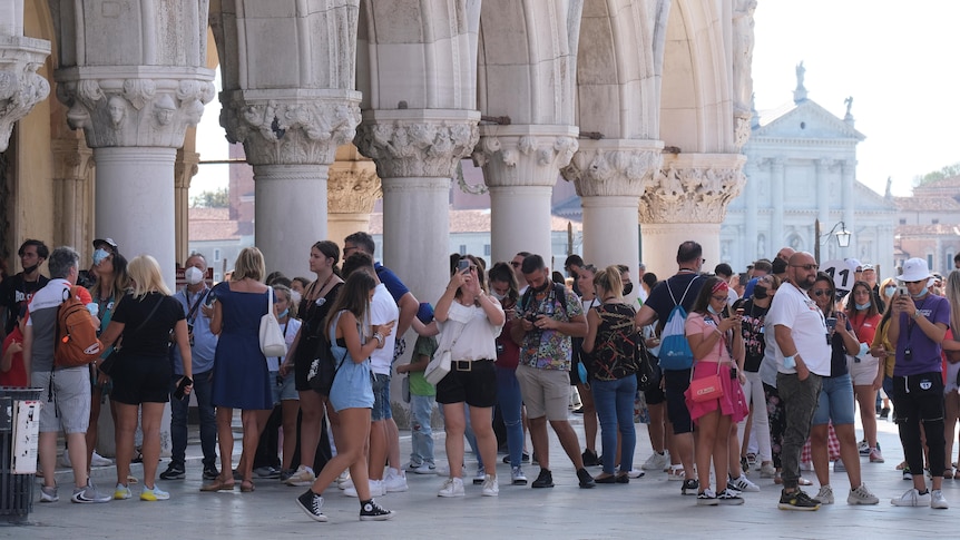 A group of tourists, part of them wearing facemasks, are pictured on St Mark's Square in Venice.