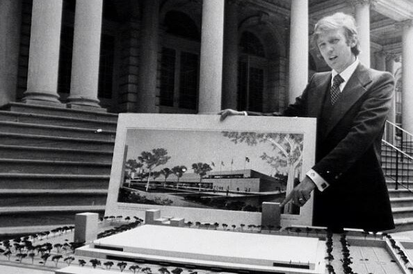Donald Trump stands behind a table modelling the convention centre