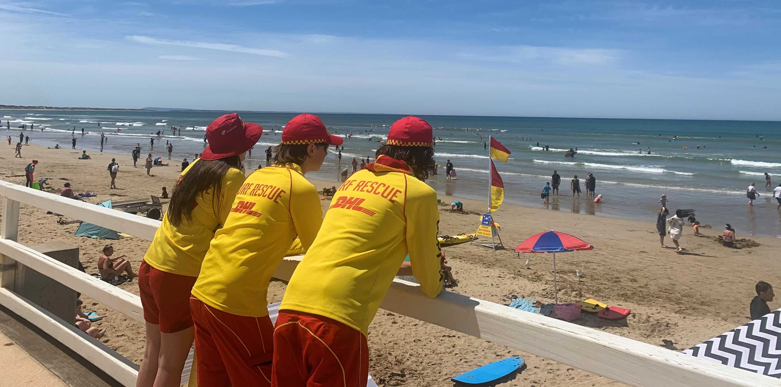 Three lifesavers lined up watching over a busy beach at Ocean Grove.