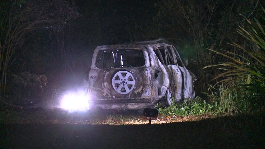 The burnt remains of a 4WD vehicle, in darkness.