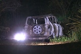 The burnt remains of a 4WD vehicle, in darkness.