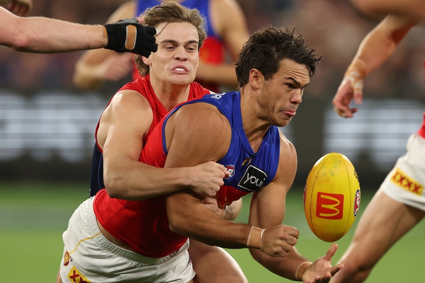 Cam Rayner of the Lions handballs while being tackled from behind
