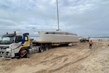 A 15-m by seven-metre yacht on the back of a semi-trailer on the beach