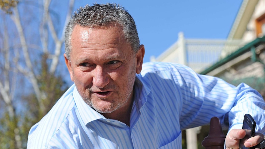 Stephen Dank, standing outside, wears a blue shirt.