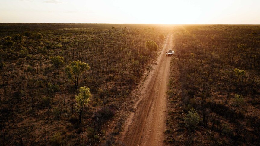 An aerial picture of a remote desert road leading off into the sunset.