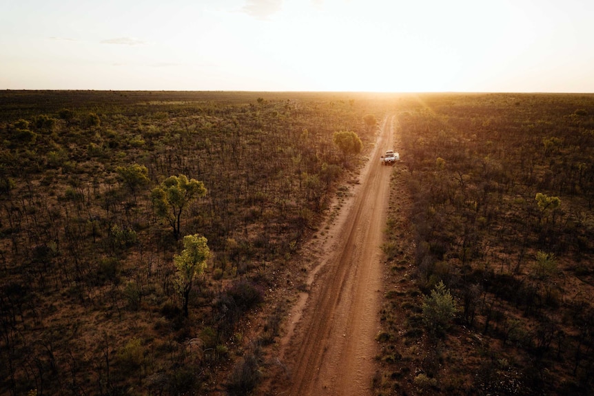 An aerial picture of a remote desert road leading off into the sunset.