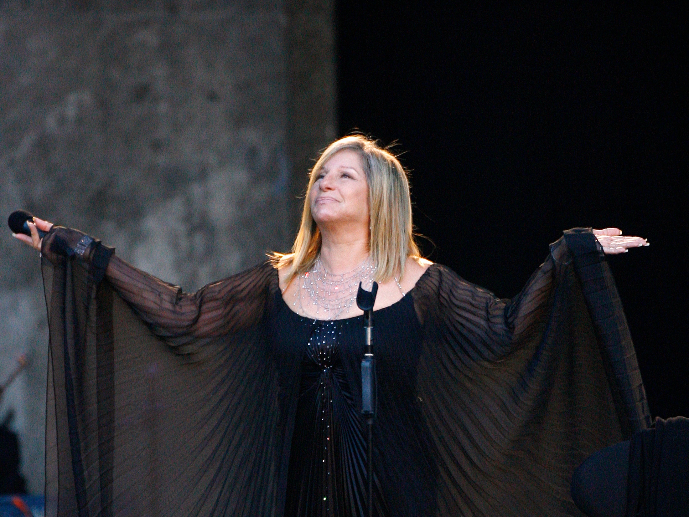 A woman in black holds her hands in a shrug 