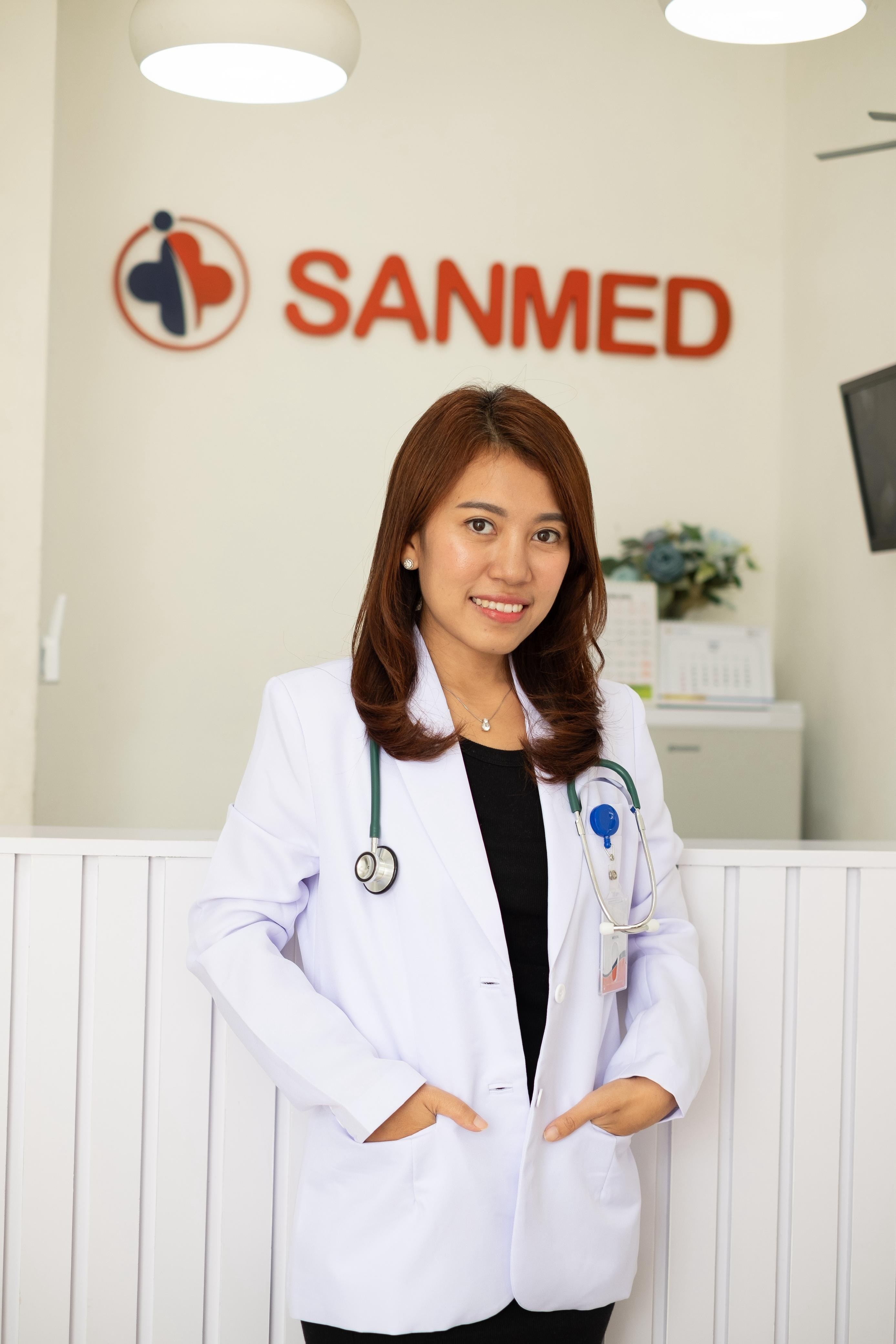 Uma mulher com um estetoscópio em pé e sorrindo para a câmera