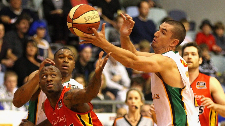 Russell Hinder and Will Blalock of the Crocodiles strip the ball from Corey Williams of the Tigers.