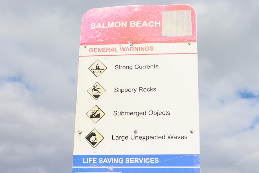 A sign notes the dangers of slippery rocks at Salmon Beach