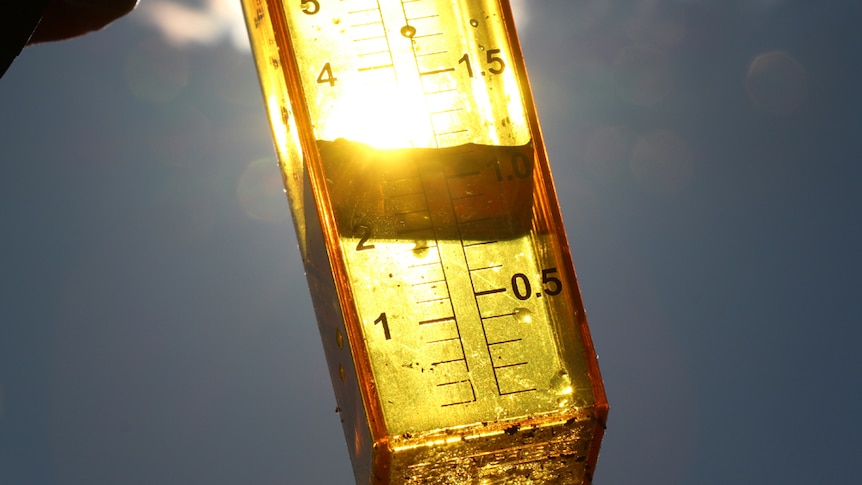 Close up of a rain gauge held up to the sun.