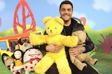 Dan Sultan clutching Big Ted, Little Ted and surround by friends on the set of Play School