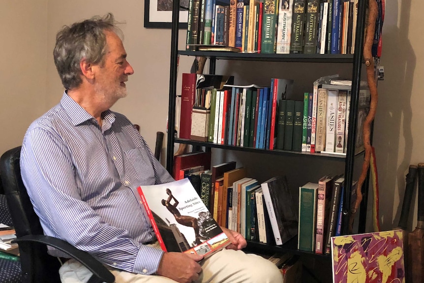 Dr Bernard Whimpress looks back at his novels on a book shelf.