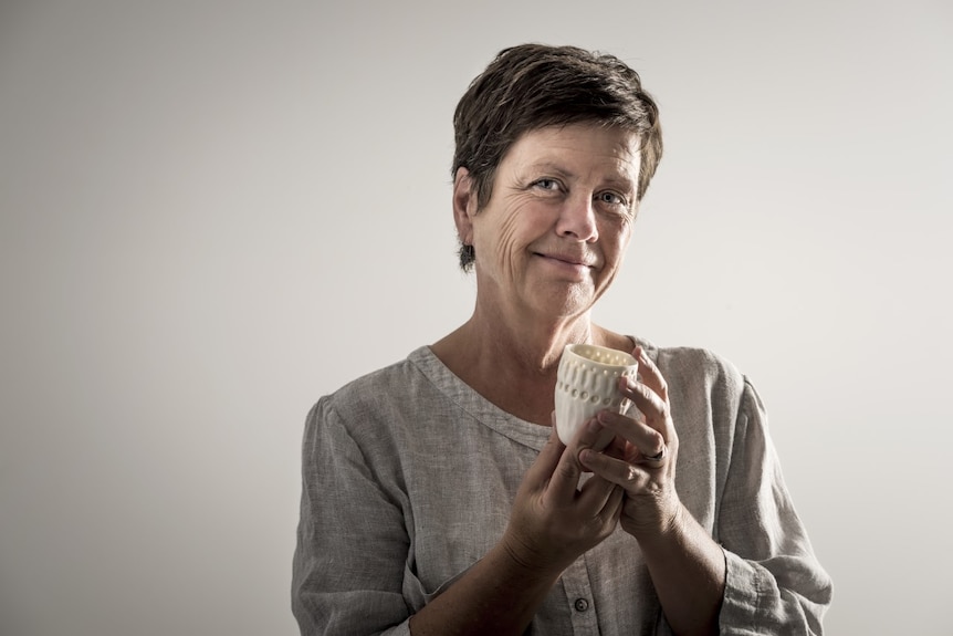 A woman holds a small pot.