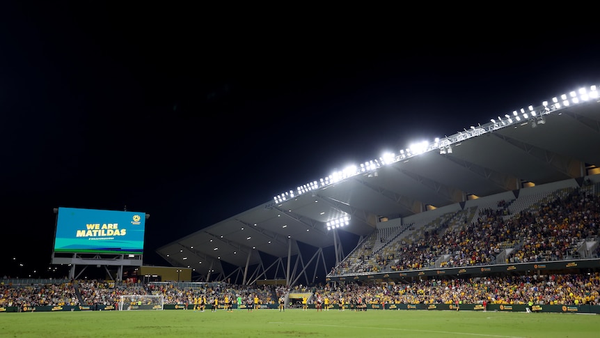 A sports stadium with fans wearing yellow during a night game