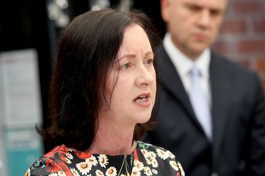 .Queensland Health Minister Yvette D'Ath, with CHO John Gerrard in the background, speaks during a press conference