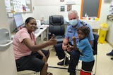 Gary Dreibergs with an Indigenous woman and a little boy in a vaccination room