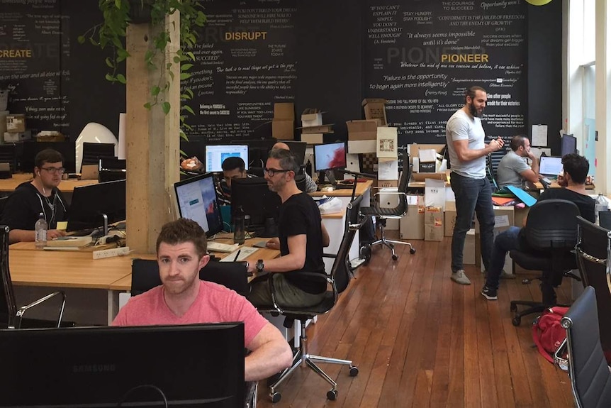 Entrepreneurs work at computers and discuss ideas at Fishburners.