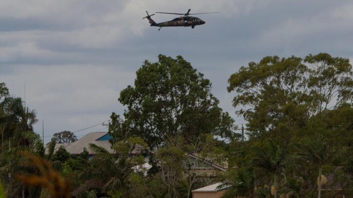 Blackhawk helicopters fly over the flooded Burnett River at North Bundaberg.