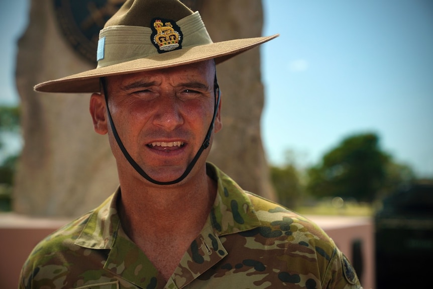 Australian army leader in green slouch hat squints in bright sunlight