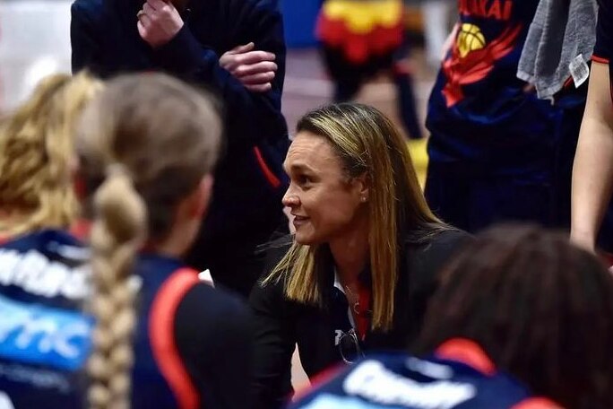 Tully Bevilaqua crouches among her team to give a speech.