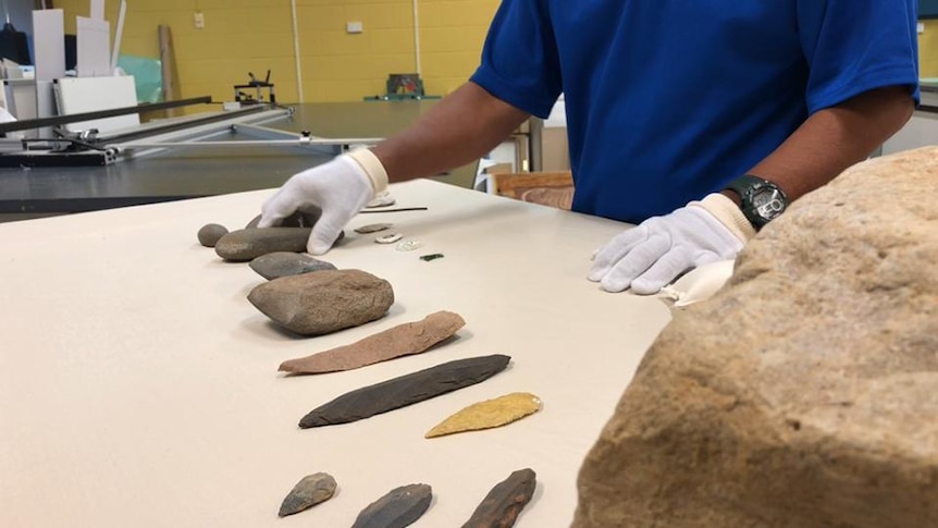 Gloved hands beside stone tools on table