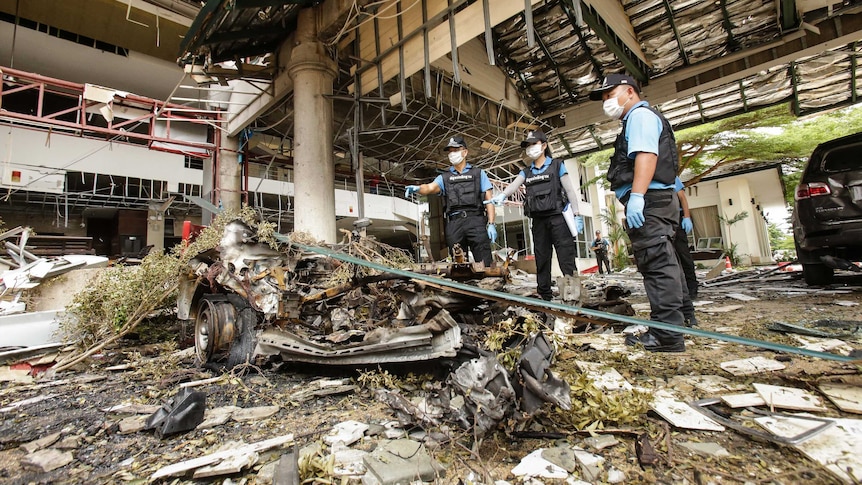 A forensics unit inspects the site of a deadly bomb blast from previous night outside of a hotel in Pattani, Thailand.