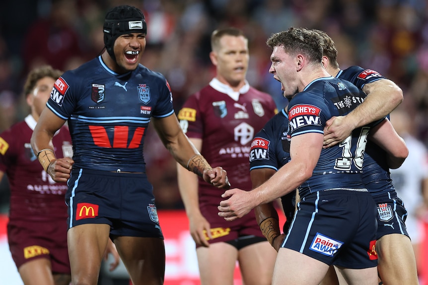 Three male NSW players celebrate a try in State of Origin I.