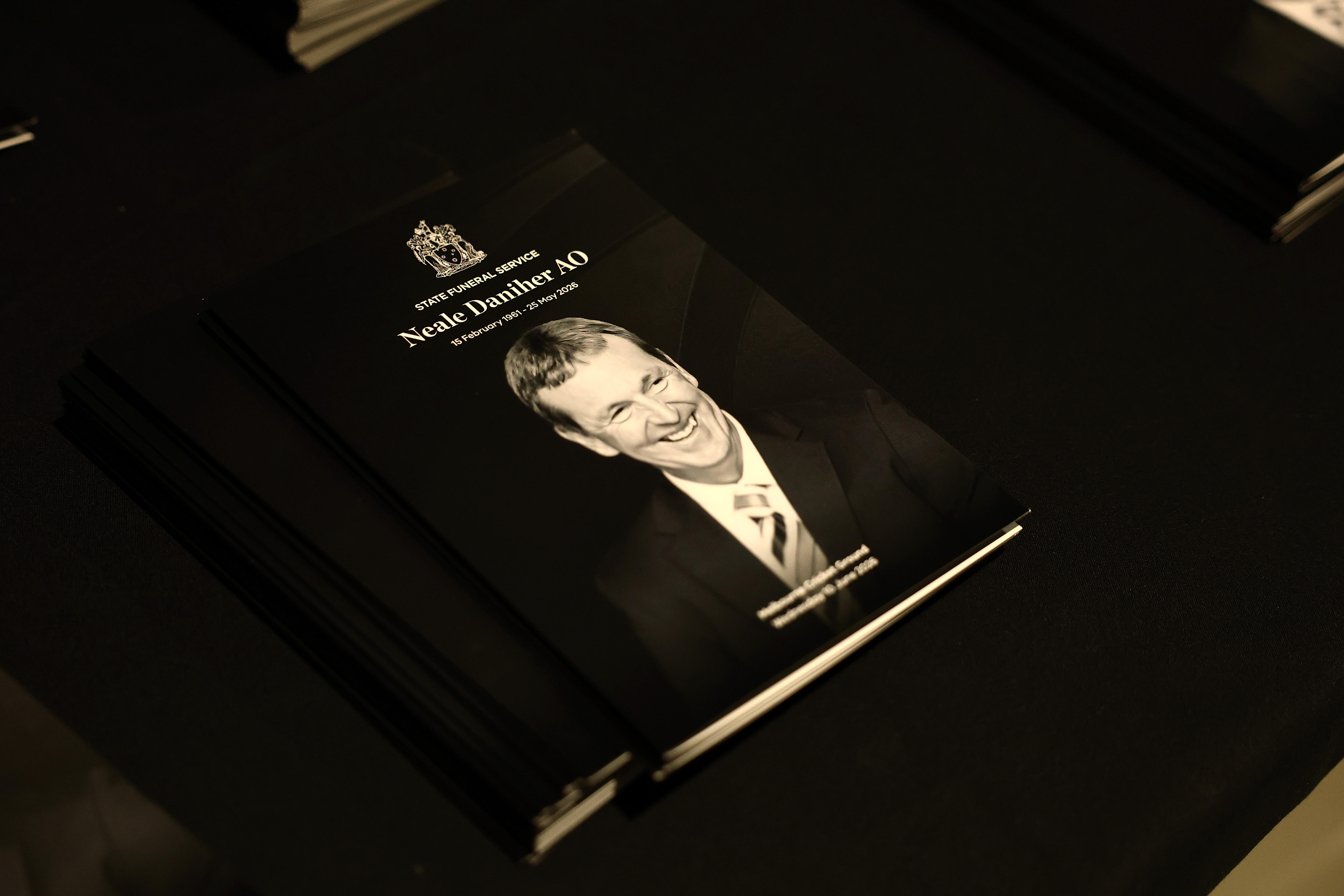 A black booklet with a black and white photo of a smiling man dressed in a suit.