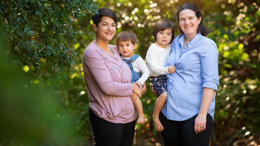 Two women holding their two kids.