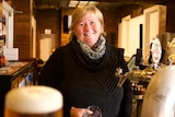 Tibooburra Hotel owner Tracey Hothcin smiles at the camera as she pours a beer in her pub. 