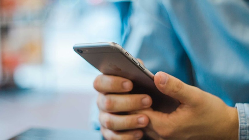 A person holds an Apple iPhone in his hand.