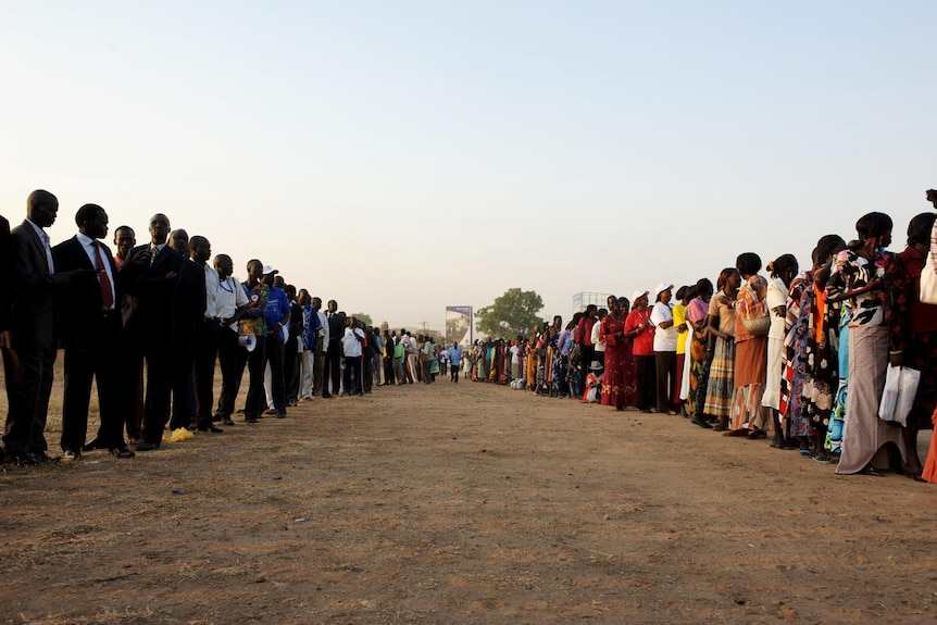 Southern Sudanese men and women line up outside a polling station (AFP: Phil Moore)
