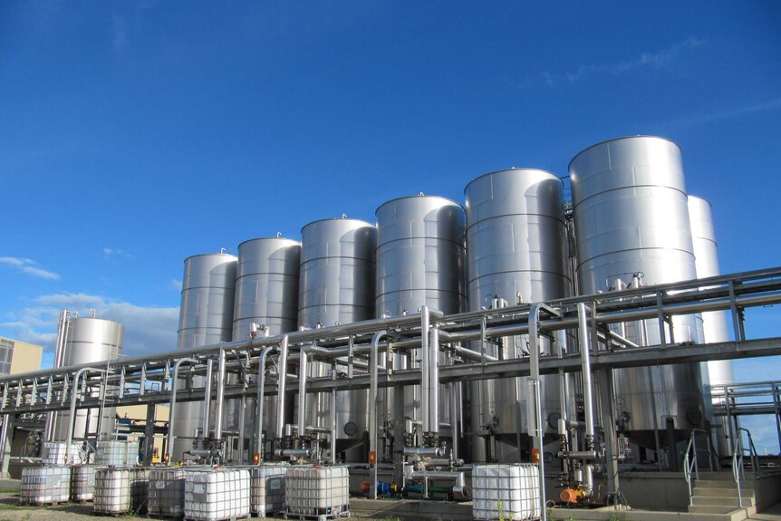 Rangées de silos en acier sous un ciel bleu. 