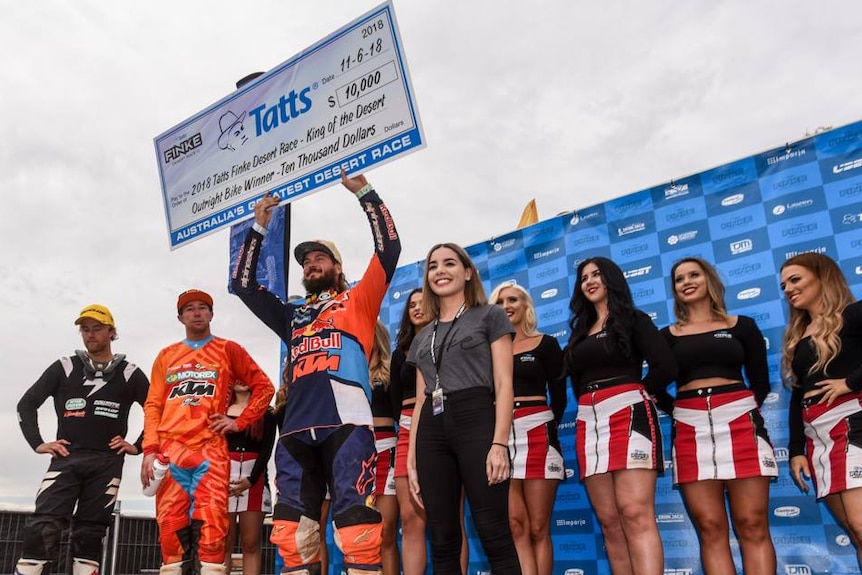 Toby Price holds up his winning cheque on the podium.