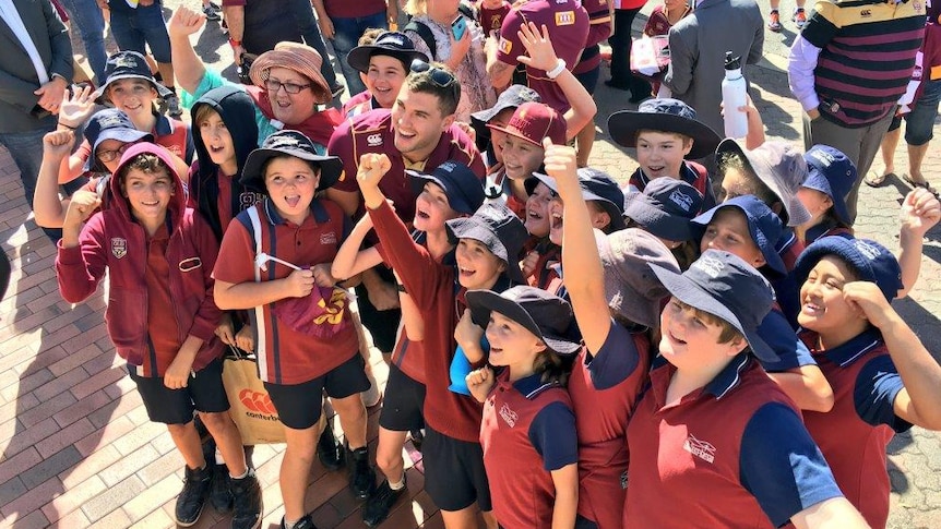 Maroons player poses for a photo in midst of young fans