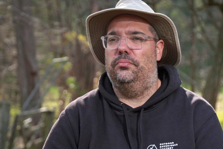 A man outside wearing glasses and a hat.