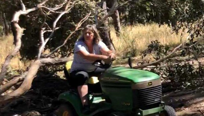 Shirley Hinkley sits on a ride-on mower on her property in Daylesford, that is surrounded by trees.