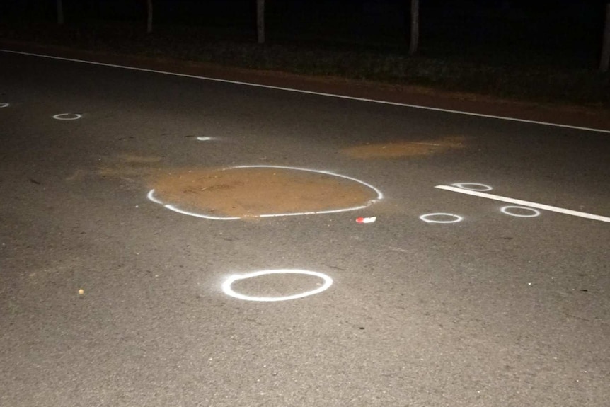 A road at night with dirt and chalk marks on it.