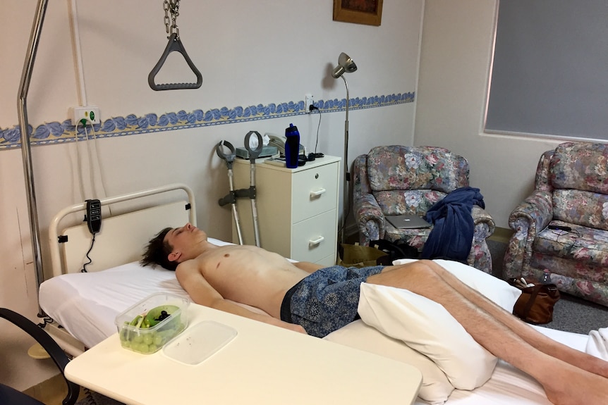 A young cancer patient lies back on his back in a hospital bed.