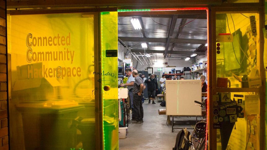 The entrance to a small warehouse space, with people working and talking inside