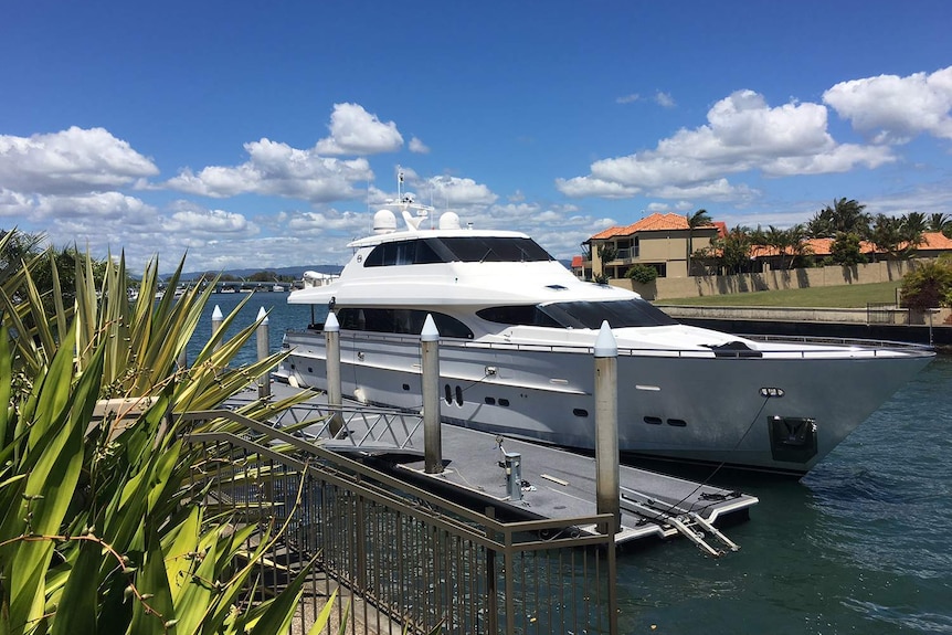 Un yate de lujo está amarrado en las tranquilas aguas de un canal de Gold Coast en un día soleado.