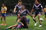 An NRL player poses in triumph after scoring a try in finals, as his teammates celebrate behind him.