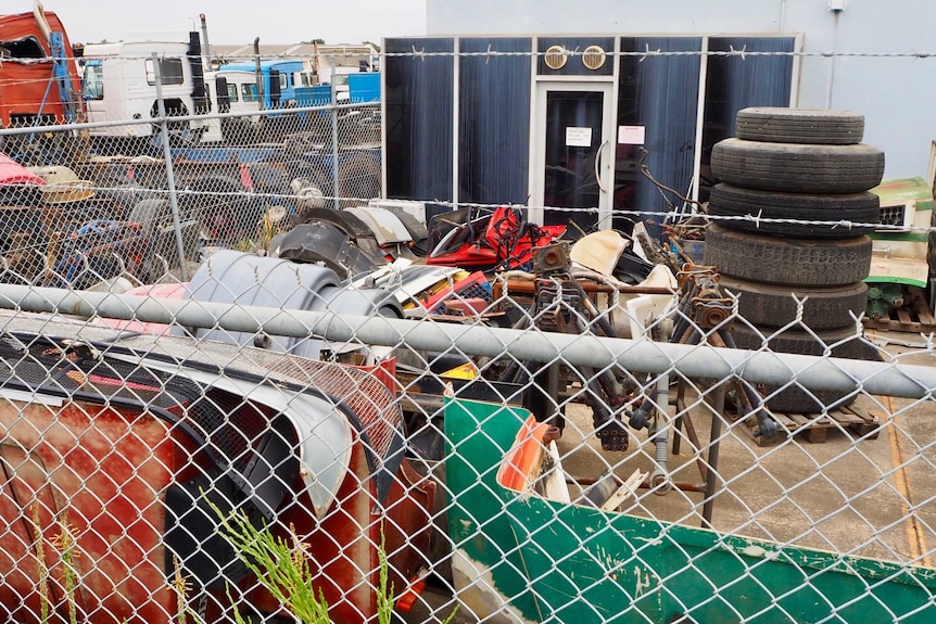 The exterior of a warehouse with car parts out the front.