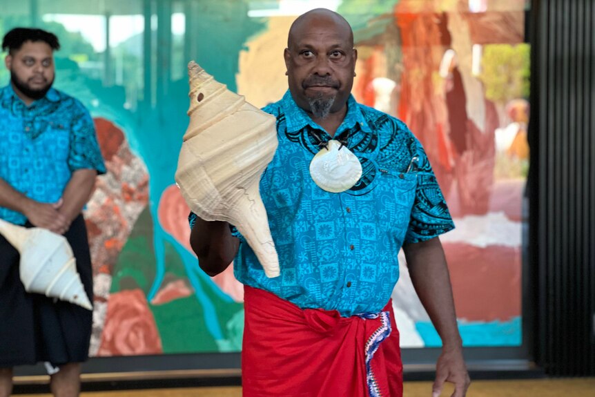 A Torres Strait Islander man with a shell performs a ceremonial dance.